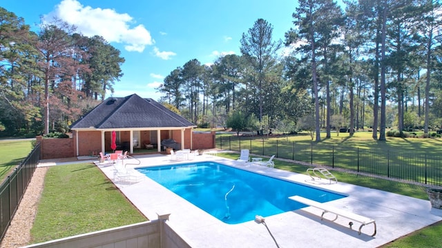 view of pool with a diving board, a patio area, and a yard