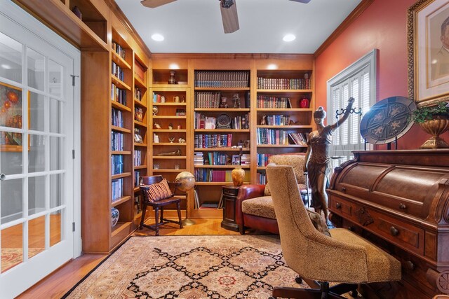 sitting room featuring ceiling fan, built in shelves, crown molding, and light wood-type flooring