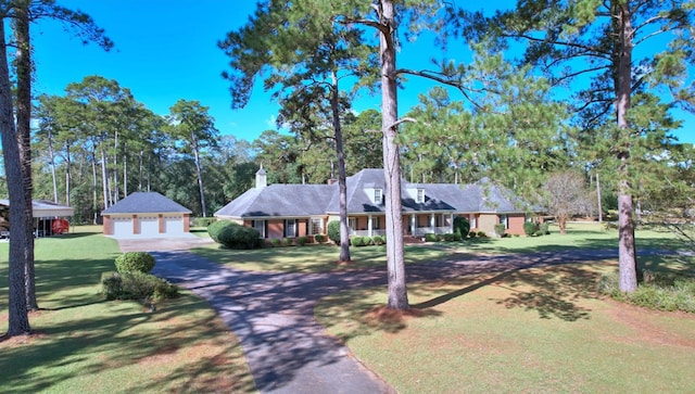 single story home with a garage, an outbuilding, and a front yard