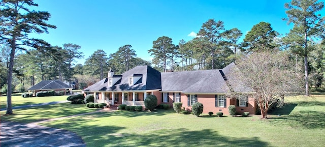 cape cod house featuring covered porch and a front lawn