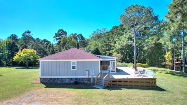 rear view of property with a lawn, a wooden deck, and a sunroom