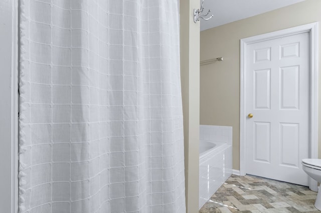 bathroom with toilet and tiled tub