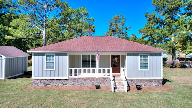 view of front of house with covered porch, a front yard, and a storage unit