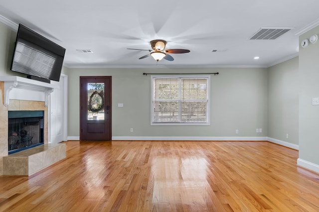 foyer featuring a tiled fireplace, light hardwood / wood-style floors, ceiling fan, and ornamental molding