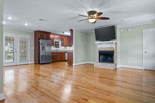 unfurnished living room featuring french doors, light hardwood / wood-style floors, sink, ornamental molding, and ceiling fan