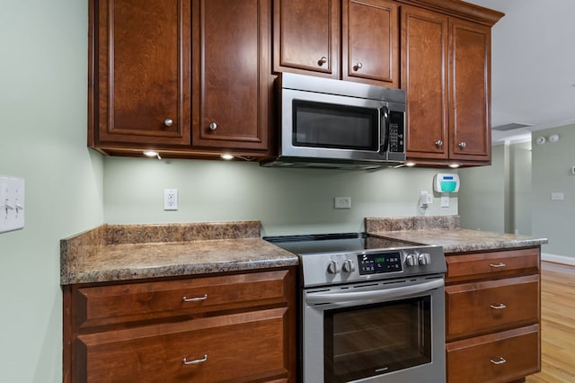 kitchen featuring light stone counters, stainless steel appliances, and light wood-type flooring