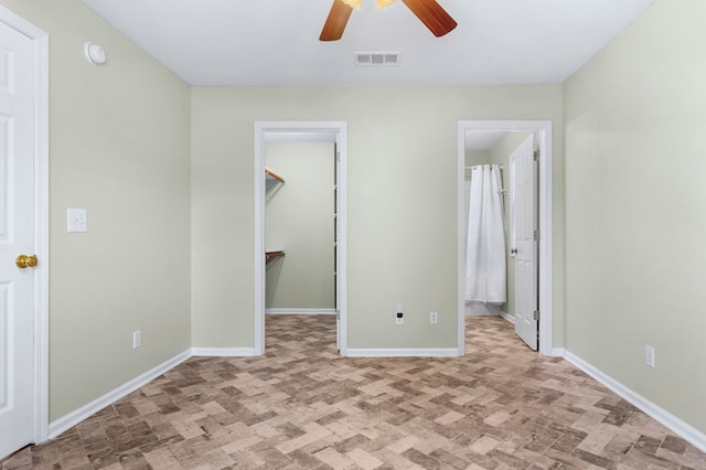 unfurnished bedroom with ceiling fan, ensuite bathroom, and a spacious closet