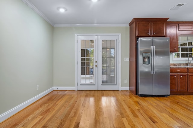 kitchen with stainless steel refrigerator with ice dispenser, light hardwood / wood-style flooring, ornamental molding, and french doors