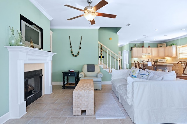 living area featuring ornamental molding, visible vents, a fireplace, and stairs