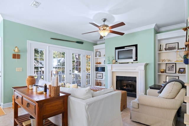 living area with visible vents, built in features, ceiling fan, ornamental molding, and a fireplace