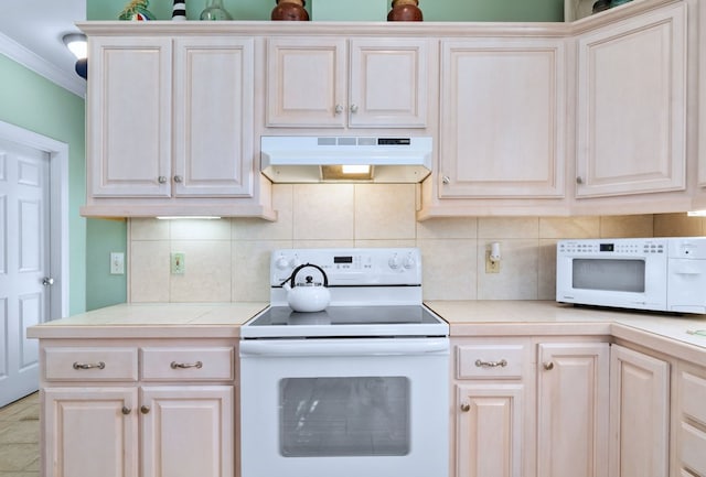 kitchen featuring under cabinet range hood, tile counters, white appliances, and backsplash