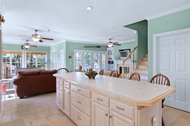 kitchen with open floor plan, ornamental molding, tile counters, and a healthy amount of sunlight