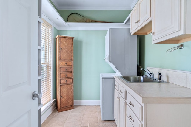 kitchen with baseboards, crown molding, white cabinetry, a sink, and light tile patterned flooring