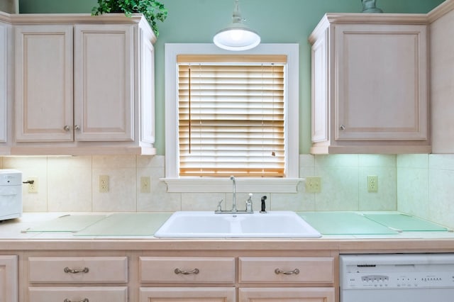 kitchen featuring dishwasher, backsplash, a sink, and tile countertops