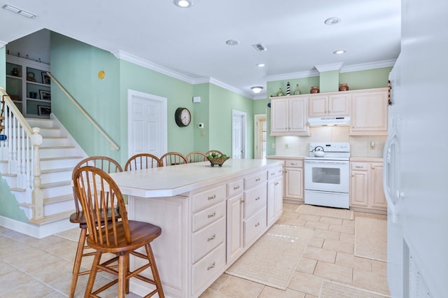 kitchen featuring a breakfast bar, under cabinet range hood, visible vents, and electric range