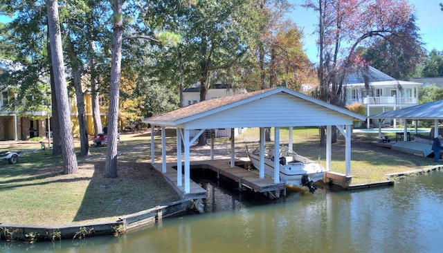 dock area with a water view, boat lift, and a lawn