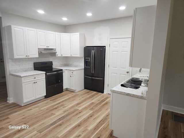 kitchen featuring white cabinets, tasteful backsplash, light stone counters, light hardwood / wood-style floors, and black appliances