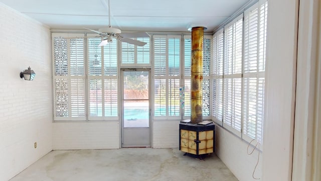 doorway to outside featuring ceiling fan, brick wall, and plenty of natural light