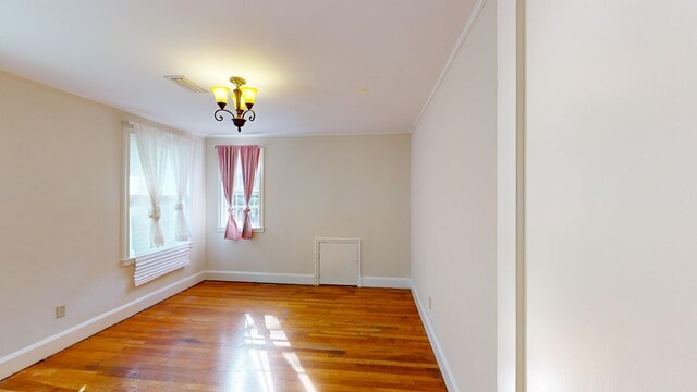 empty room featuring a chandelier and wood-type flooring