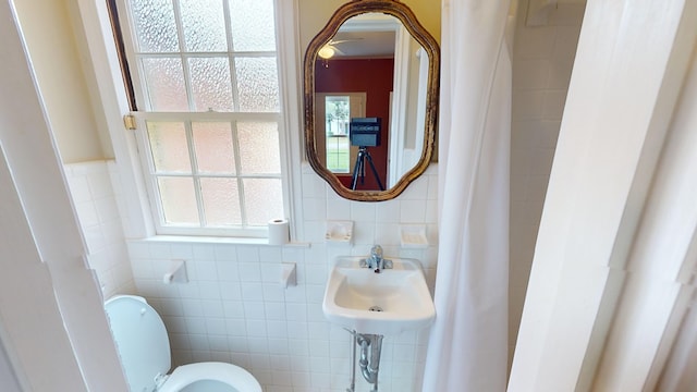 bathroom featuring toilet and tile walls