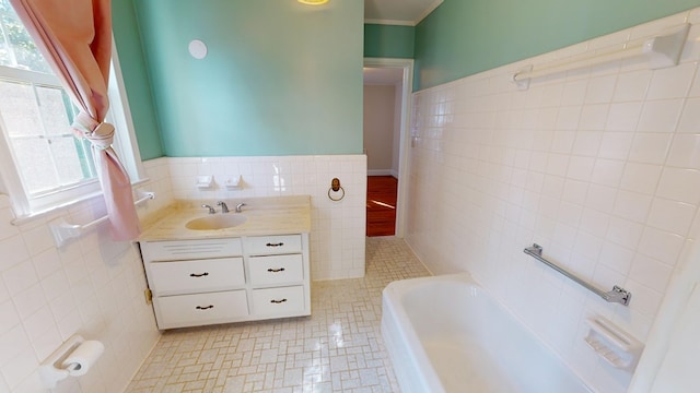 bathroom with tile walls, a tub to relax in, vanity, and tile patterned flooring