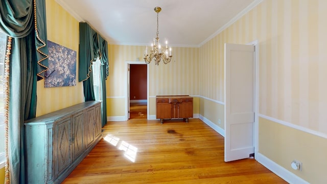 unfurnished dining area with light wood-type flooring, a chandelier, and ornamental molding