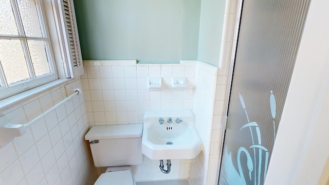 bathroom with sink, tile walls, and toilet