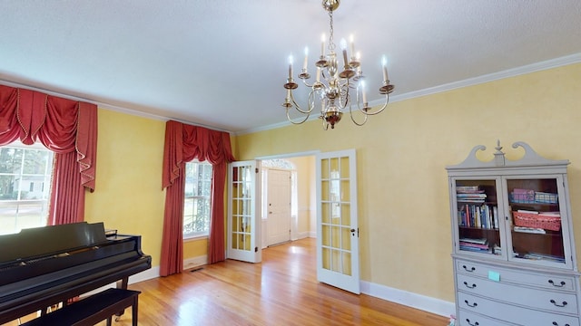 misc room featuring crown molding, a healthy amount of sunlight, light wood-type flooring, and french doors