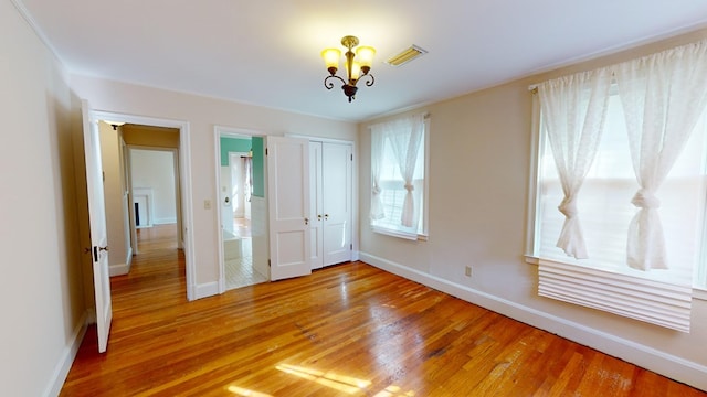 unfurnished bedroom with hardwood / wood-style flooring, a closet, and an inviting chandelier