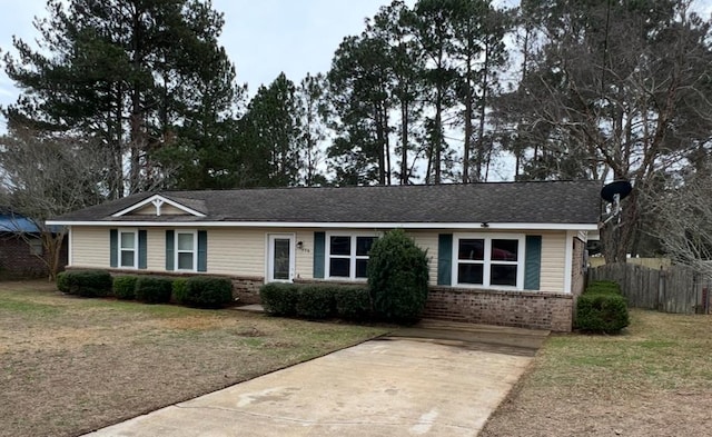 ranch-style house featuring brick siding, fence, and a front lawn