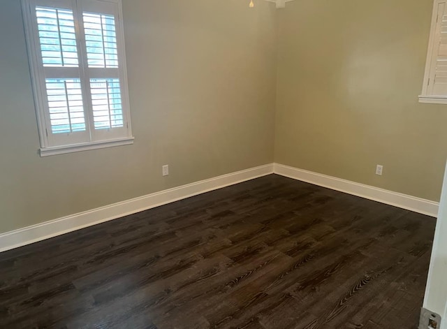 unfurnished room featuring dark wood-style floors and baseboards