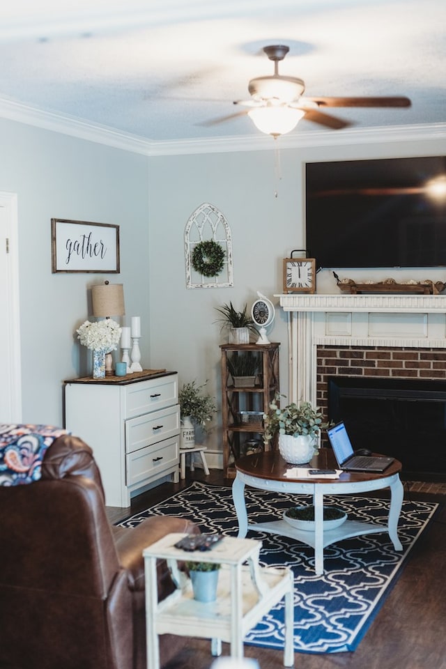 living room featuring ceiling fan, dark hardwood / wood-style flooring, ornamental molding, and a fireplace