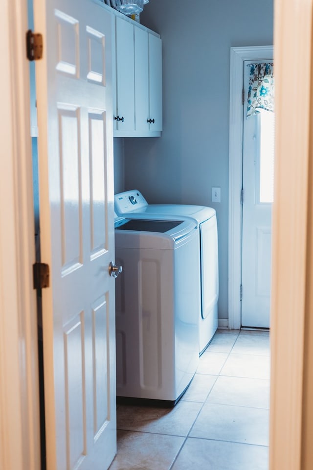 washroom featuring light tile patterned flooring, a wealth of natural light, cabinets, and independent washer and dryer