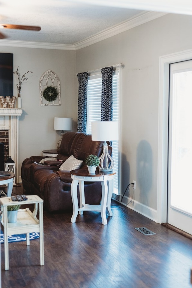 living room with dark wood-type flooring, ornamental molding, and a healthy amount of sunlight