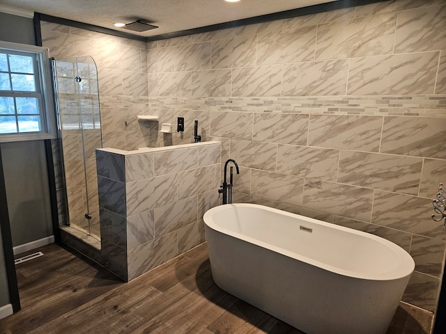 bathroom with visible vents, tiled shower, a soaking tub, wood finished floors, and tile walls