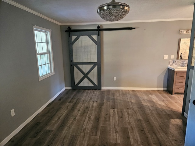 unfurnished dining area featuring a barn door, crown molding, baseboards, and dark wood-style flooring