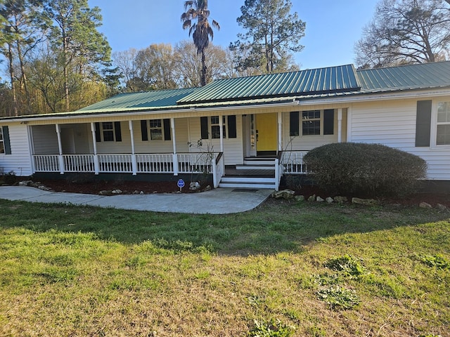 view of front of house featuring covered porch, metal roof, and a front lawn