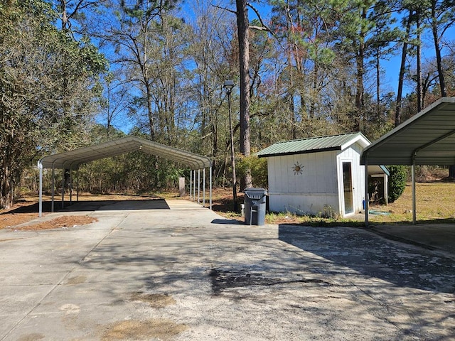 view of parking featuring a detached carport, driveway, and a shed