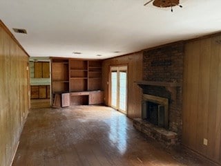 113 Sharon Cir, Americus, GA 31709 - unfurnished living room featuring wood walls, a brick fireplace, and wood finished floors