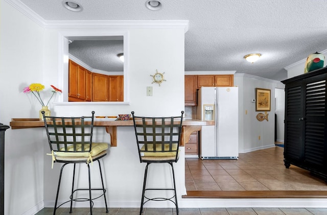 kitchen with light tile patterned floors, white refrigerator with ice dispenser, a breakfast bar area, and crown molding