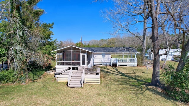 back of property with a deck, a lawn, and a sunroom