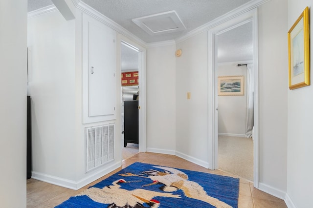 hallway with light tile patterned floors, attic access, visible vents, and a textured ceiling