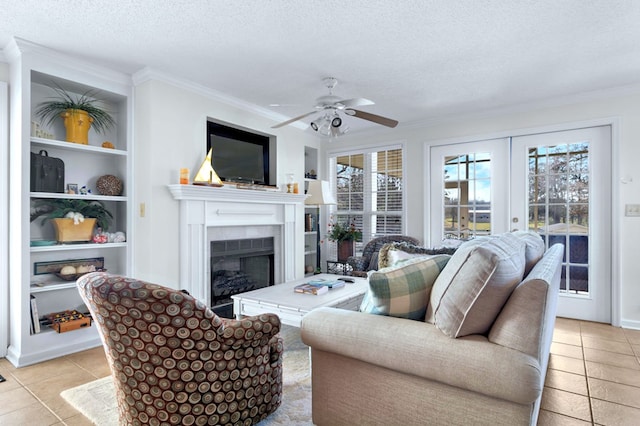 living area featuring french doors, crown molding, light tile patterned floors, a tiled fireplace, and a textured ceiling