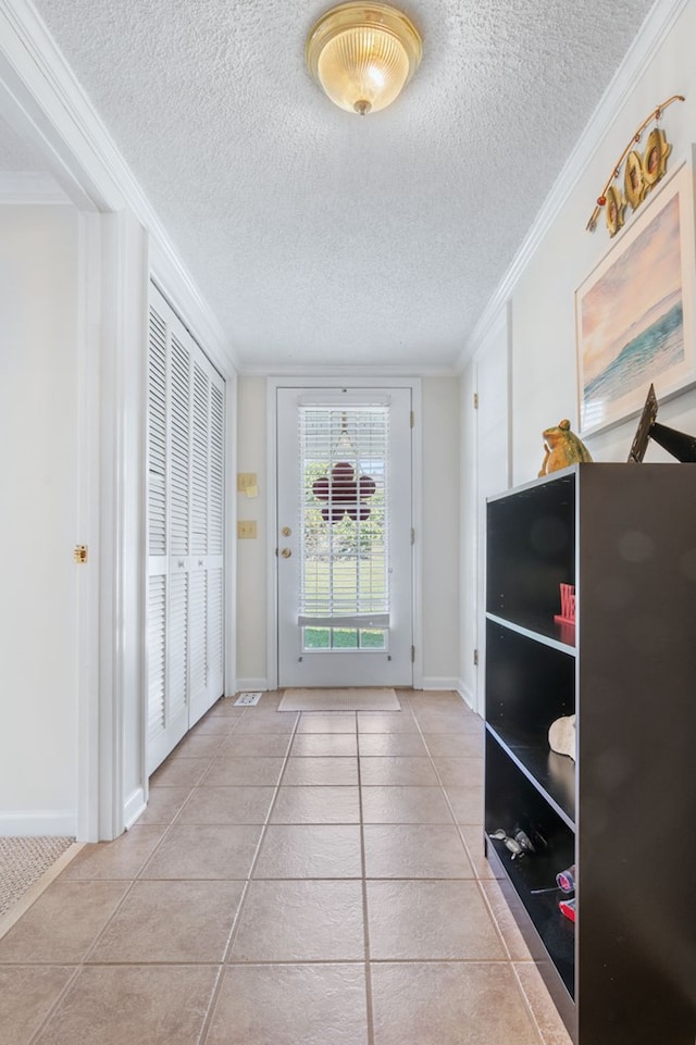 entryway featuring a textured ceiling, baseboards, tile patterned flooring, and crown molding