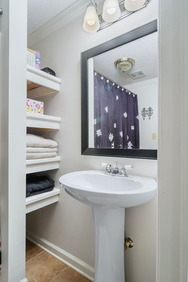 bathroom featuring crown molding, visible vents, and a textured ceiling