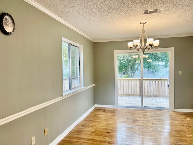 unfurnished dining area featuring light hardwood / wood-style floors, a wealth of natural light, a textured ceiling, and an inviting chandelier