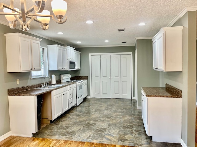 kitchen with hanging light fixtures, sink, white cabinetry, white appliances, and a textured ceiling