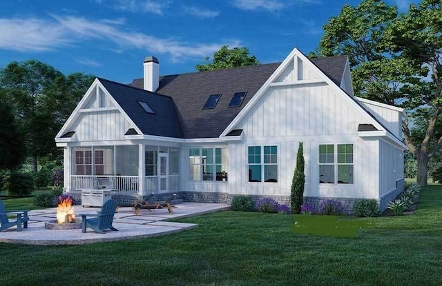 back of house featuring a lawn, a sunroom, an outdoor fire pit, and a patio