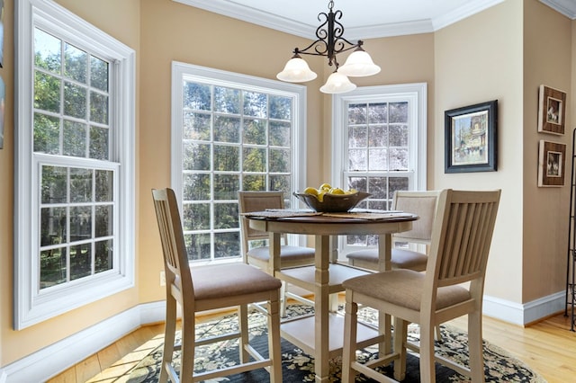 dining area with crown molding, a chandelier, and light hardwood / wood-style flooring