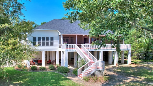 rear view of property with a sunroom, a patio, a deck, and a yard